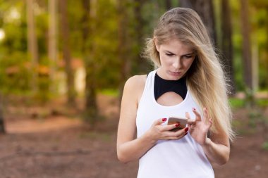 Güzel sarışın genç kadın cep telefonunu - görüntü günbatımı kontrol mesajları Park