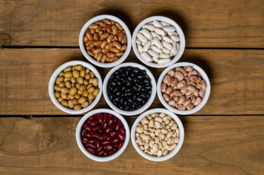 ahşap kahverengi zemin üzerine beyaz pot içinde fasulye yedi çeşitleri.