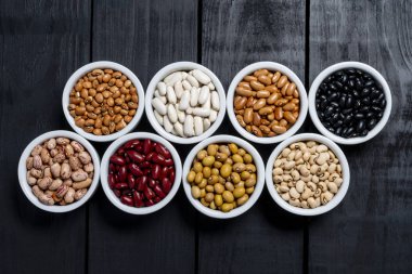 Sekiz siyah arka plan üzerine beyaz pot içinde fasulye çeşitleri.