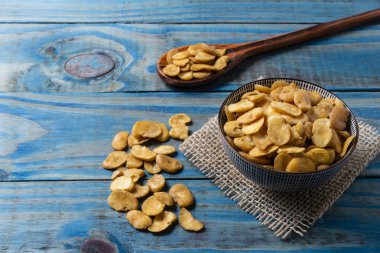 Mavi çam üzerinde seramik tencere içinde kavrulmuş fava.