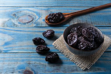 Seramik kap içinde mavi çam ahşap üzerinde kuru erik.