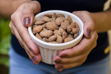 Esmer modeli el beyaz pot kızarmış badem ile tutarak.