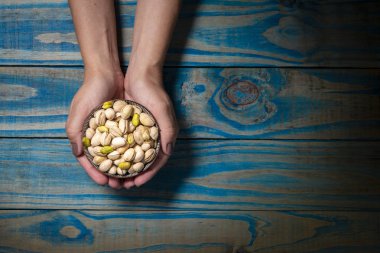 Seramik kap mavi ahşap zemin üzerine Antep fıstığı ile tutarak esmer modeli.