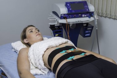 Güzellik kliniği. Sarışın genç kadın miyostimülasyonu alıyor.