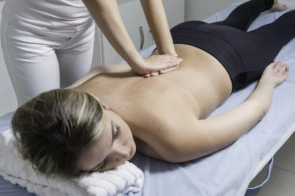 Beautiful blond woman receiving Shiatsu Treatment from a therapist.