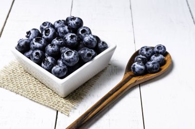 Beyaz ahşap arka plan üzerinde pot içinde Taze yaban mersini.