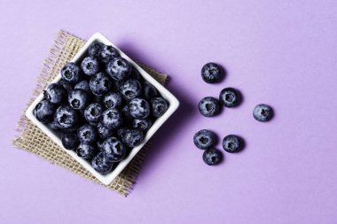 Mor arka plan üzerinde pot içinde Taze yaban mersini.