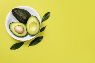 Sarı arka plan üzerinde seramik tencere içinde Avokado.