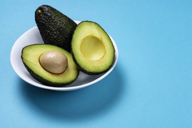 Siyan arka planda seramik tencere içinde avokado.