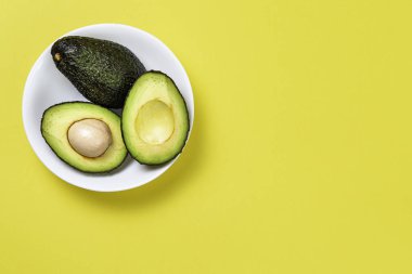 Sarı arka plan üzerinde seramik tencere içinde Avokado.