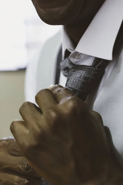 Black man fixing tie for wedding.