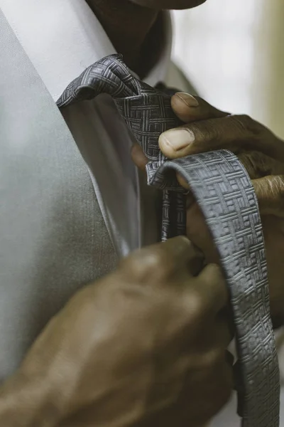 Black man fixing tie for wedding.