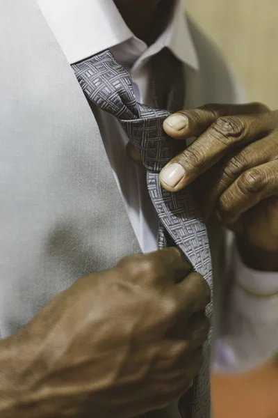 Black man fixing tie for wedding.