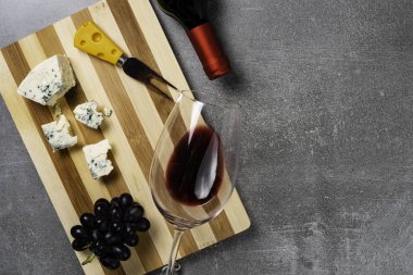 Beton arka plan üzerinde şarap ile peynir ve cam çizgili tahta. Kopyalama Alanı.