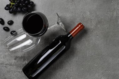 Beton arka planda şarap, kadeh ve üzüm şişesi. Kopyalama Alanı.