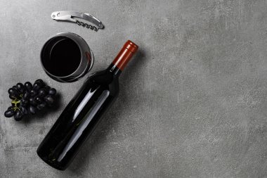 Şarap şişesi, cam, açacağı ve çimento kaplı üzümler. Boşluğu Kopyala.