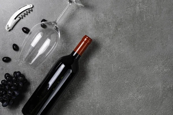 Wine bottle, glass, opener and grapes on concrete background. Copy Space.