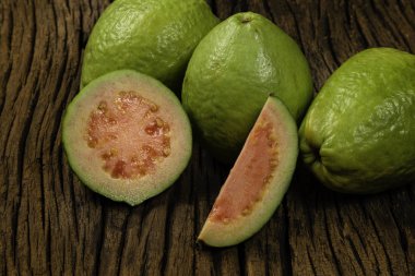 Ahşap arka planda taze kırmızı guavalar. Ahşap doku.