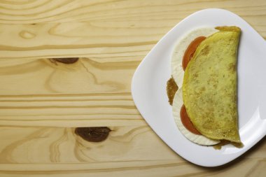 Casabe (bammy, beiju, bob, biju). Manyok gözleme (tapioca) caprese salatası ile (domates, mozzarella) plaka pinus ahşap arka plan üzerinde. Seçici odaklama.