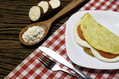 Crepioca. Eski ahşap arka plan üzerinde tabakta peynir ve domates ile manyok (tapyoka) Pancake. Seçici odaklama.