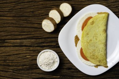 Crepioca. Eski ahşap arka plan üzerinde tabakta peynir ve domates ile manyok (tapyoka) Pancake. Seçici odaklama.