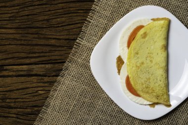 Crepioca. Eski ahşap arka plan üzerinde tabakta peynir ve domates ile manyok (tapyoka) Pancake. Seçici odaklama.
