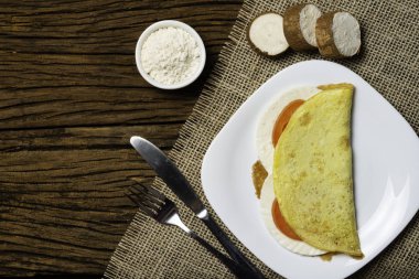 Crepioca. Eski ahşap arka plan üzerinde tabakta peynir ve domates ile manyok (tapyoka) Pancake. Seçici odaklama.