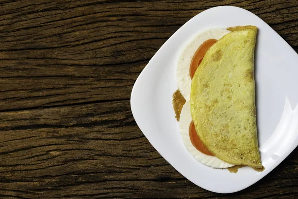 Crepioca. Eski ahşap arka plan üzerinde tabakta peynir ve domates ile manyok (tapyoka) Pancake. Seçici odaklama.