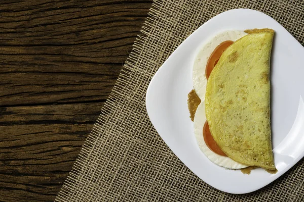 Crepioca. Eski ahşap arka plan üzerinde tabakta peynir ve domates ile manyok (tapyoka) Pancake. Seçici odaklama.