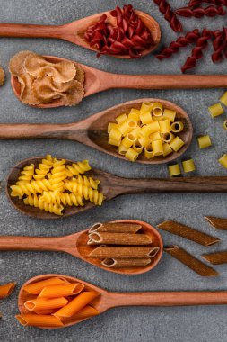 Masadaki tahta kaşıklarda farklı makarna tipleri. Üst görünüm.