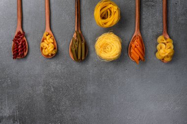 Masadaki tahta kaşıklarda farklı makarna tipleri. Üst görünüm.