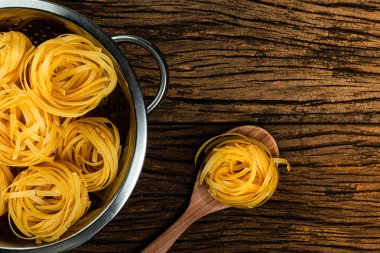 Eski ahşap arka planda pişirme için hazırlanan yumurta ile makarna Fettuccine.
