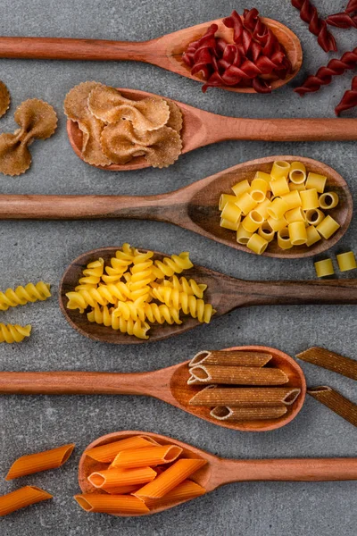 Different Pasta Types Wooden Spoons Table Top View — Stock Photo, Image