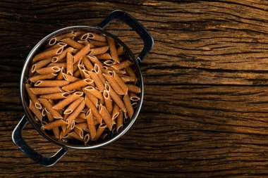 Eski ahşap arka planda su süzgeçinde penne integral.