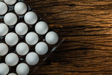 Tepsi kutusunda birçok beyaz tavuk yumurtası yiyecek. Metin için arka plan alanı için eski ahşap arka plan alanı.