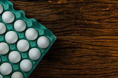 Tepsi kutusunda birçok beyaz tavuk yumurtası yiyecek. Metin için eski ahşap arka plan alanı.