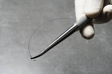 Doktor mavi naylon cerrahi iplik ile ameliyat için iğne tutucu tutan.