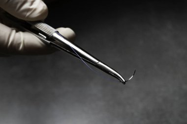 Doktor mavi naylon cerrahi iplik ile ameliyat için iğne tutucu tutan.
