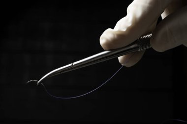 Doktor mavi naylon cerrahi iplik ile ameliyat için iğne tutucu tutan.