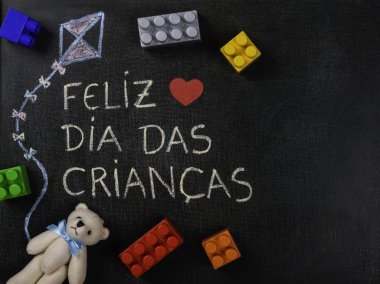 Blackboard Feliz dia das criancas (Portekizce) yazılı. Uçurtma Çizim ve Ride parçaları ve ayı. Kopyalama alanı.