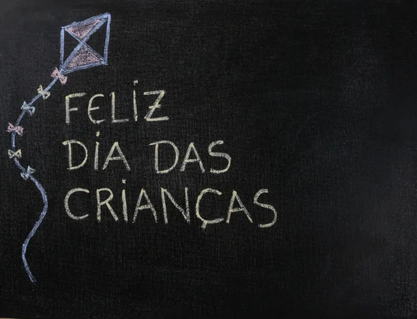 Blackboard Feliz dia das criancas (Portekizce) yazılı. Uçurtma Çizimi. Kopyalama alanı.