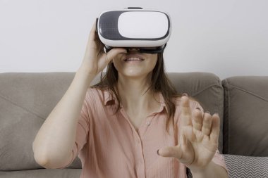 Vr'ı kullanan kadın bir eliyle kanepede oturmuş, bir eliyle sanal bir nesneye dokunma hissi yaşıyor..