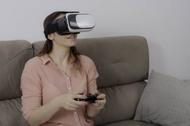 Vr'ı kullanan kadın evinde sanal oyun oynayarak kanepede oturmuş.