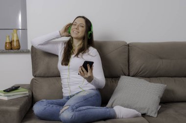 Güzel, genç kadın kanepede oturarak onu kulaklık ile müzik dinlerken rahatlatıcı.