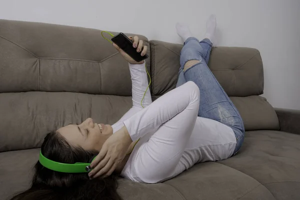 Junges Schönes Mädchen Mit Kopfhörer Auf Der Couch Liegend Musik — Stockfoto