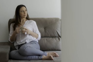 Kanepede oturup çay içen ve dinlenen bir kadın. Kopyalama alanı.