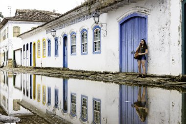 Güzel model Paraty tarihi şehirde telefonda konuşurken mavi ahşap kapı da ayakta, Rio de Janeiro, Brezilya.