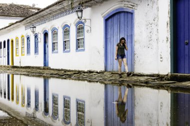 Güzel model Paraty tarihi şehirde telefonda konuşurken mavi ahşap kapı da ayakta, Rio de Janeiro, Brezilya.