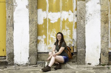 Paraty tarihi şehirde sarı kapı üzerinde oturan güzel model, Rio de Janeiro, Brezilya.