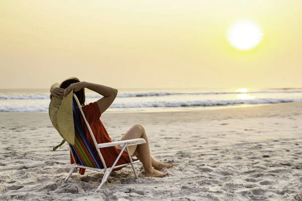 Modelo Sosteniendo Sombrero Sol Sentado Silla Playa Relajante Durante Puesta — Foto de Stock